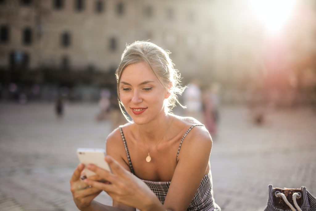 ragazza legge email sul telefono in città