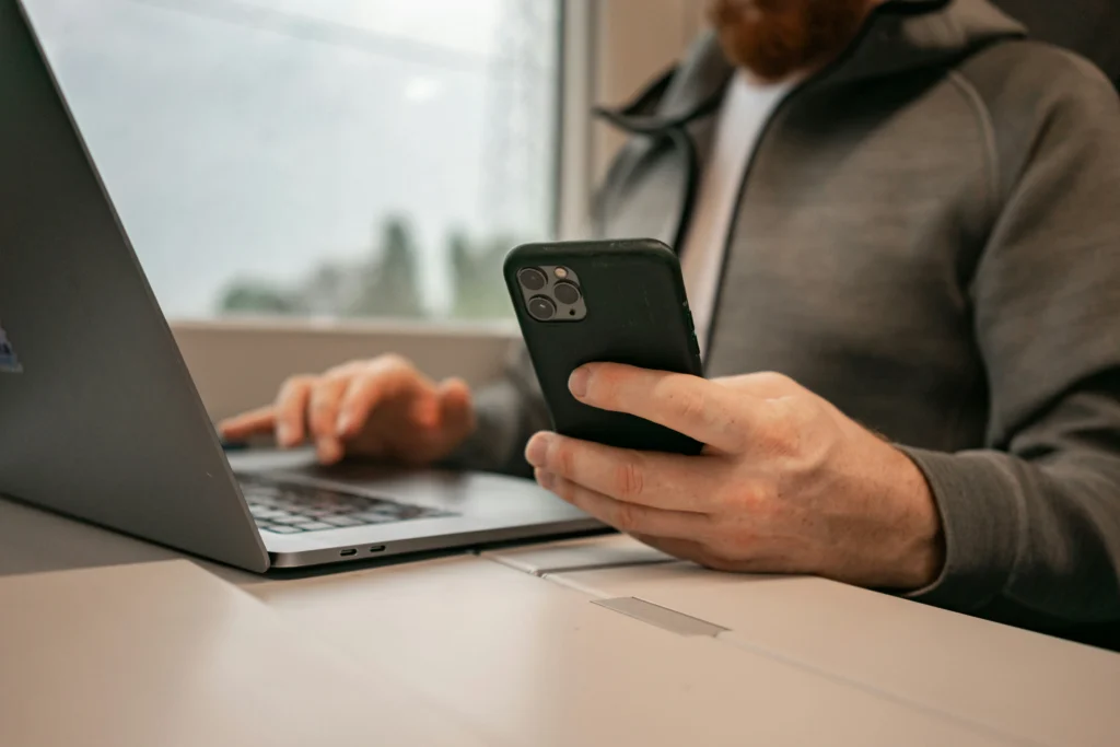 Un titolare di salone gestisce le prenotazioni online sul telefono mentre usa il laptop